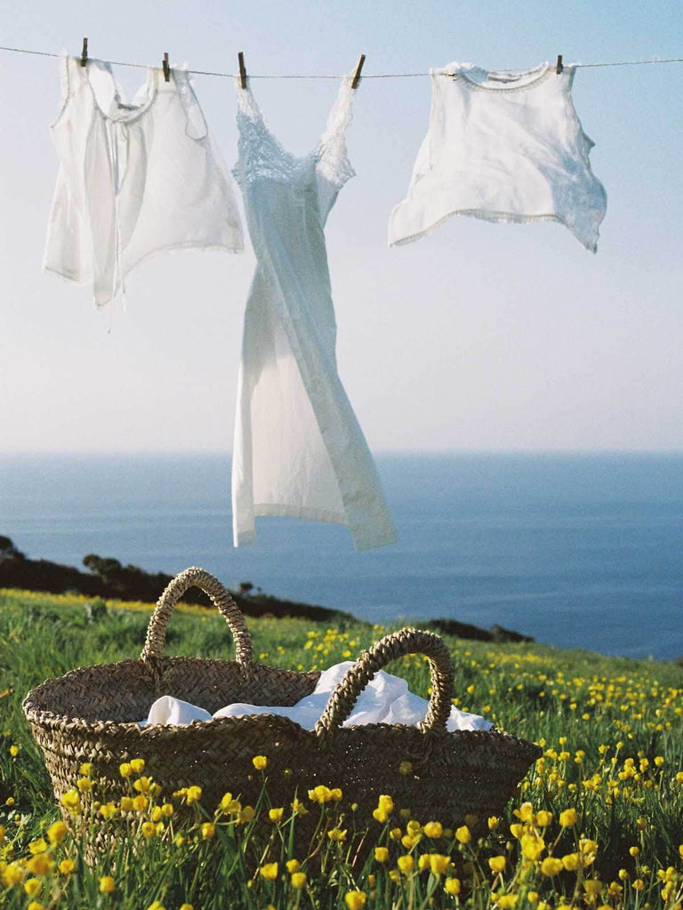 Large natural woven beldi basket being used to hang laundry out to dry on a washing line by the sea