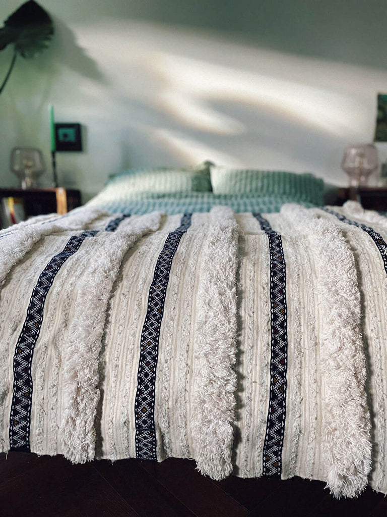 Vintage Moroccan Handira Blanket draped on a bed in a cosy bedroom