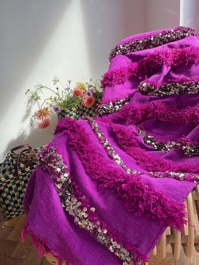 Vibrant pink Moroccan handira blanket draped on a chair