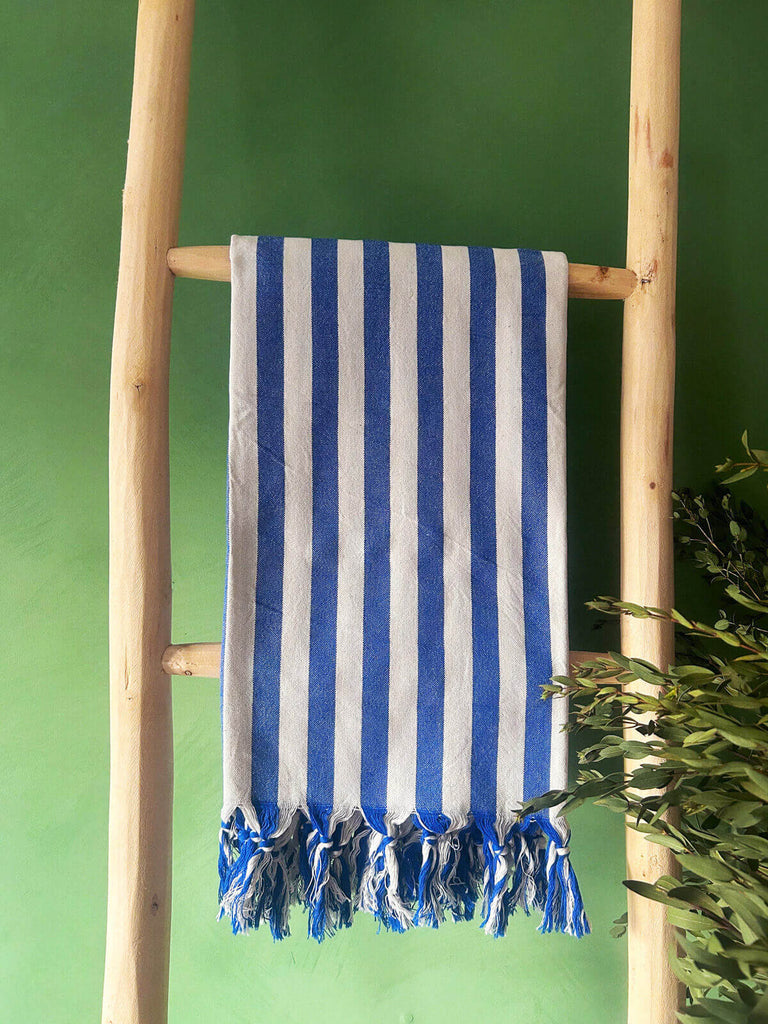 Brighton Stripe hammam towel in blue and white wide stripes on a wooden ladder