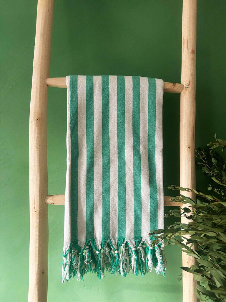 Brighton stripe cotton hammam towel in green hanging on a wooden ladder