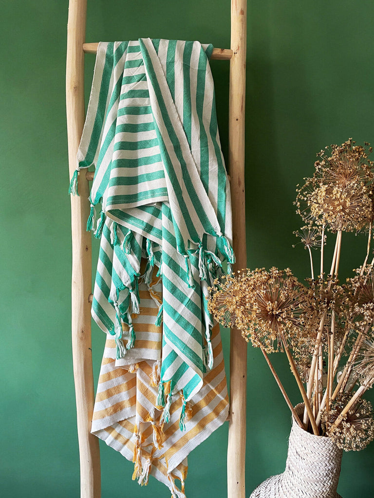 Brighton cotton hammam towels with a wide seaside stripe and fringe, casually draped on a rustic wooden ladder | Bohemia Design