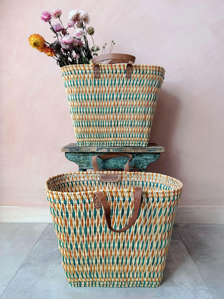 Two Tall rectangular woven reed shopper baskets with teal and orange pattern and leather handles for shopping or colourful home storage