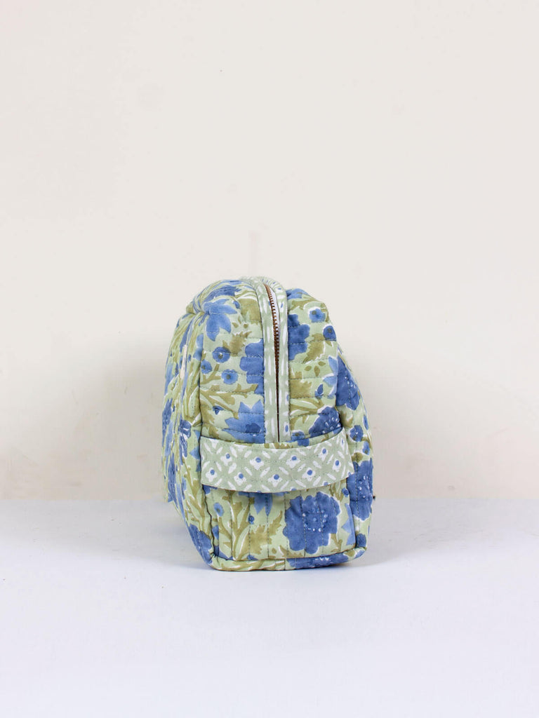 Side view showing the zip and handle of a quilted floral print washbag in sage and blue