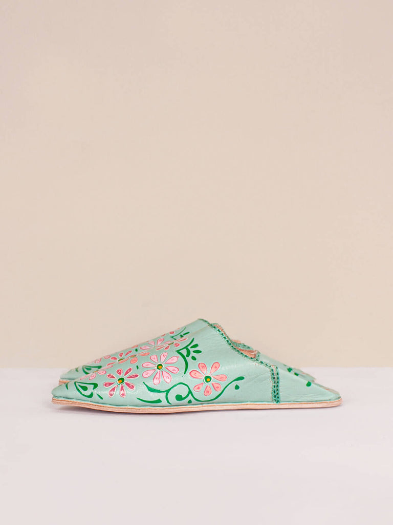A pair of pointed babouche slippers in a sage green leather with colourful hand painted blooms in pink and green