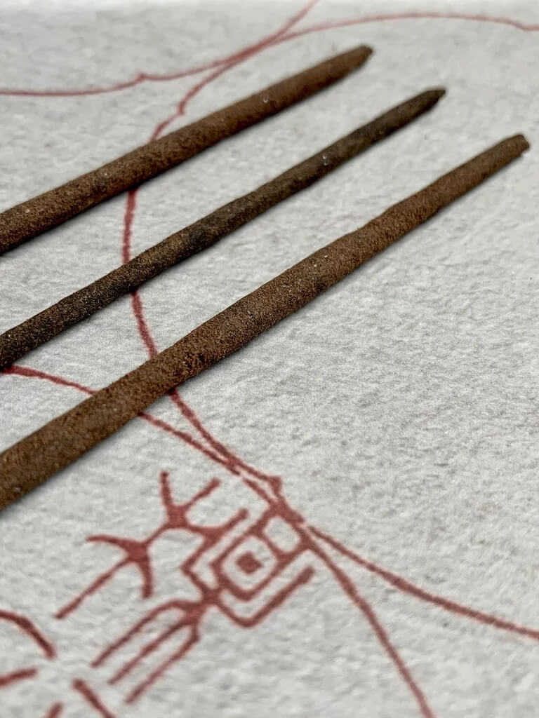 Three incense sticks on a textile background