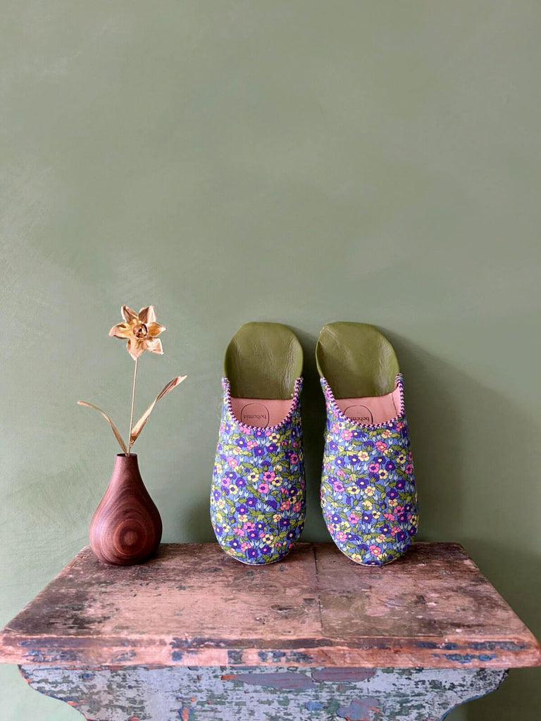 Floral Liberty print babouche slippers with green leather on a rustic stool