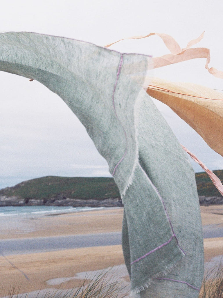 Linen Scarf in sage green hanging on a washing line by the sea