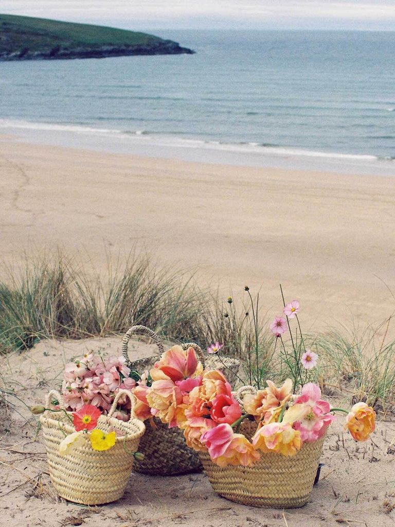 Small and mini Market Baskets on a beach filled with summer flowers