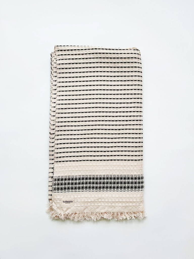 Beautifully tactile, waffle-textured Milos Check Hammam Towel with a subtle charcoal striped pattern and finished with hand-tied tassel fringe by Bohemia Design