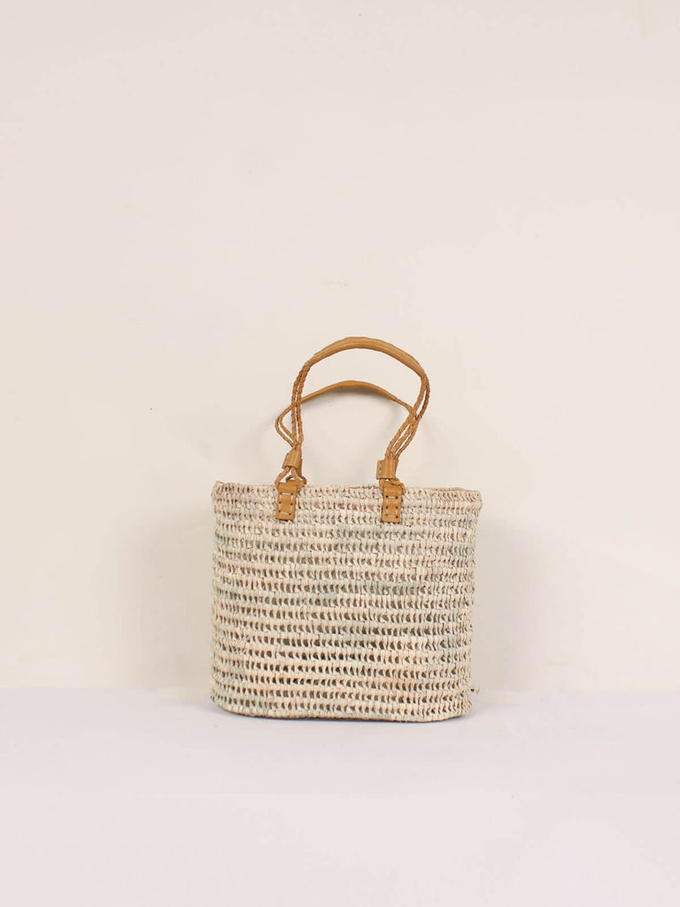 A small open weave basket with mustard colour pleated leather handles
