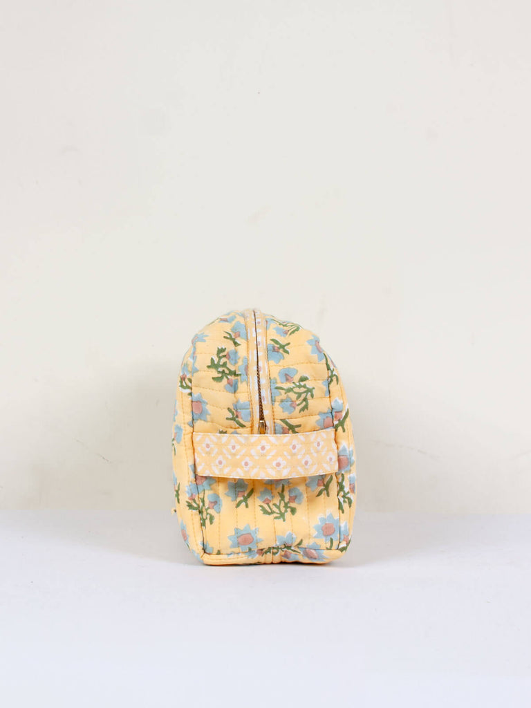 Side showing zip and handle of a Posie block printed quilted washbag with pastel yellow, blue and green floral pattern