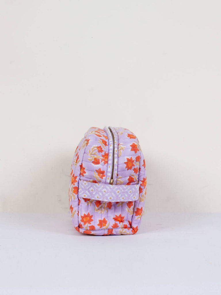 Side showing zip and handle of a Posie block printed quilted washbag with lilac and orange floral pattern