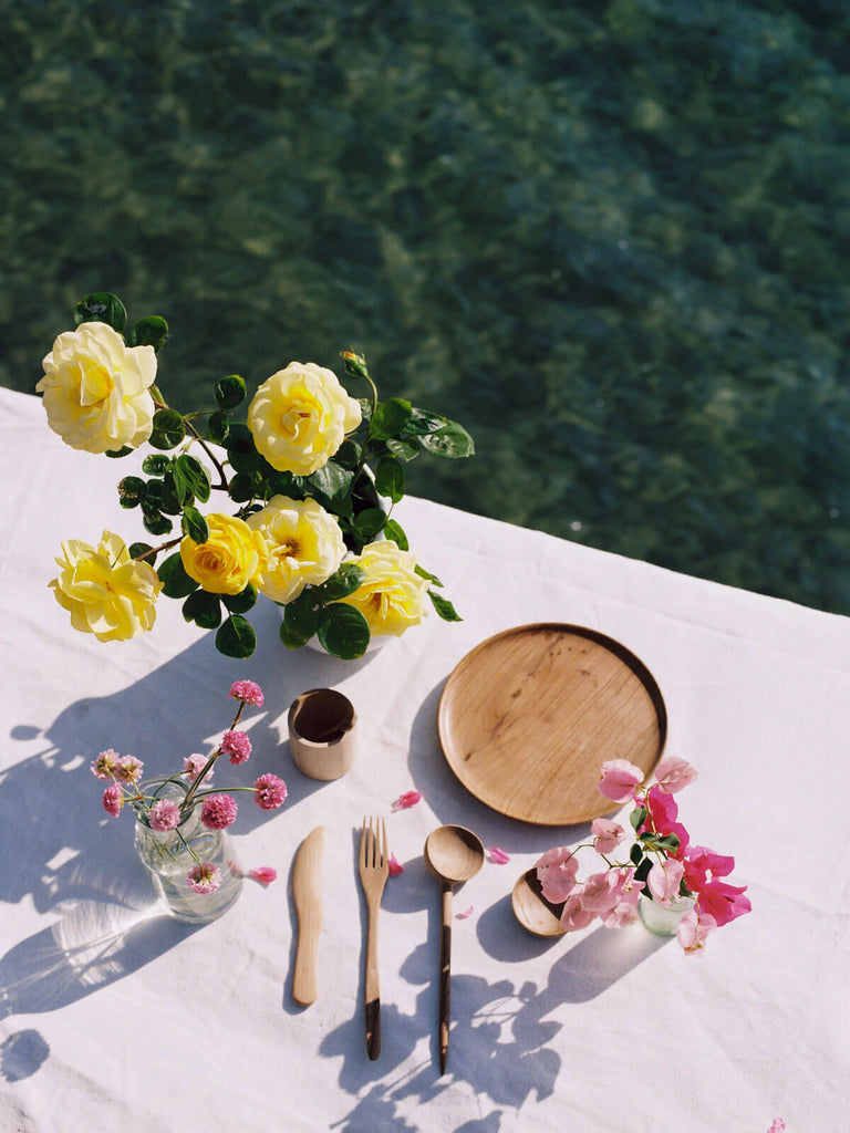 Walnut Wood Plate on an outdoor table setting by the sea with handcrafted wooden tableware and yellow roses
