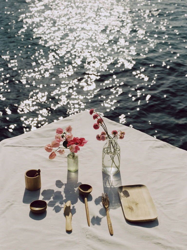 Table setting by the sea with handcarved wooden fork, knife, spiin and tray.