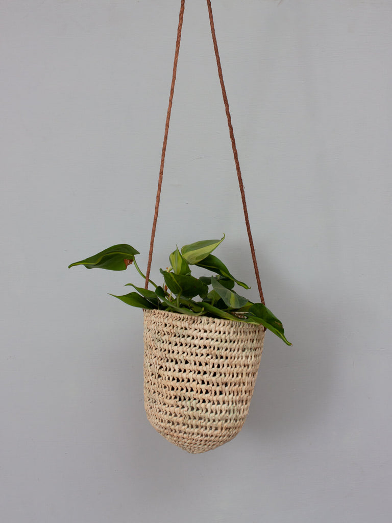 Small natural woven indoor hanging basket with finely braided tan leather