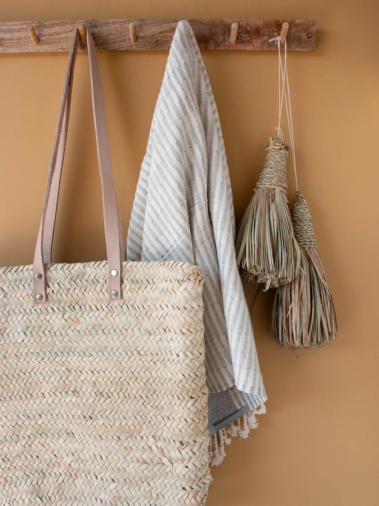 Asilah shopper basket hanging with hammam towel on hooks against a mustard wall