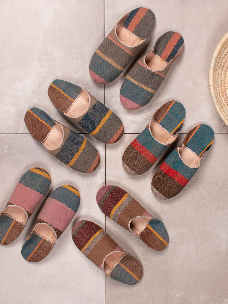 Group of Bohemia design boujad babouche slippers in camel stripe pattern against grey tiles