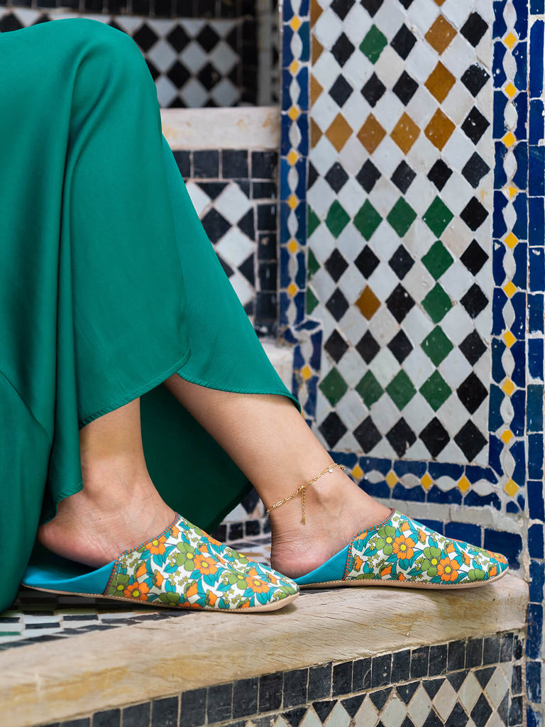 Model wearing Bohemia Design Margot babouche slippers in pink and aqua floral pattern at a Moroccan riad 