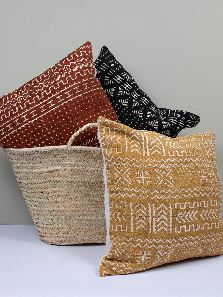 Three cushions with mudcloth patterns in a basket 