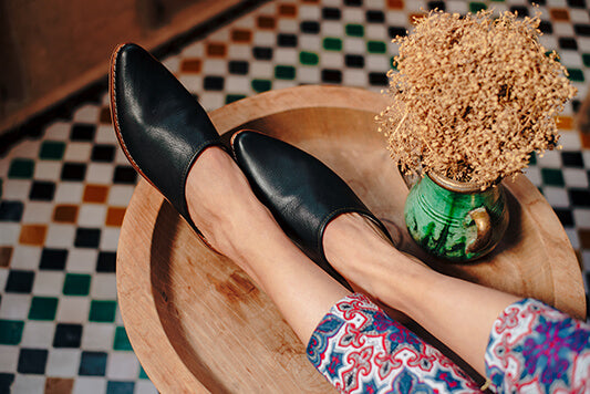 Bohemia-leather-mules-black-on-model-with-Moroccan-tiles-and-dried-flowers