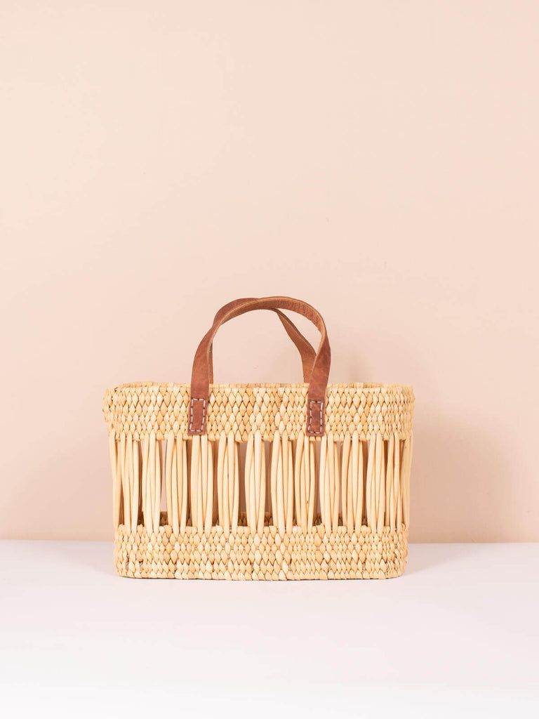 Small decorative woven reed basket bag with natural leather handles