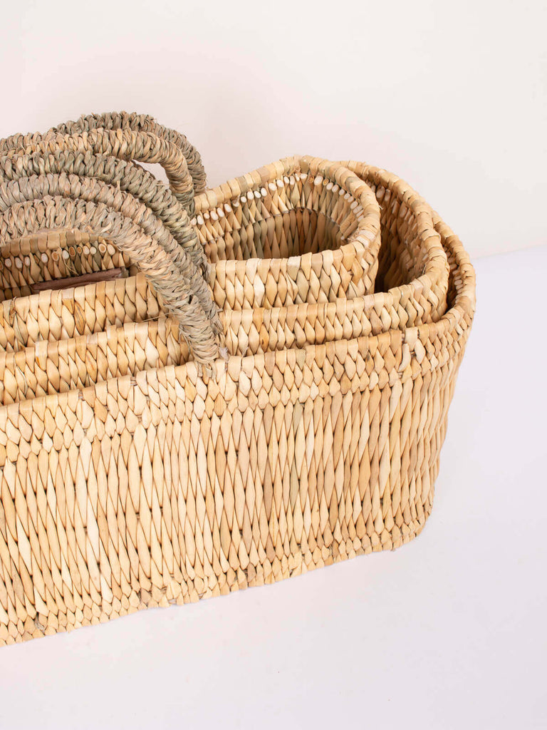 Set of three available sizes of nesting woven reed storage baskets for useful storage options
