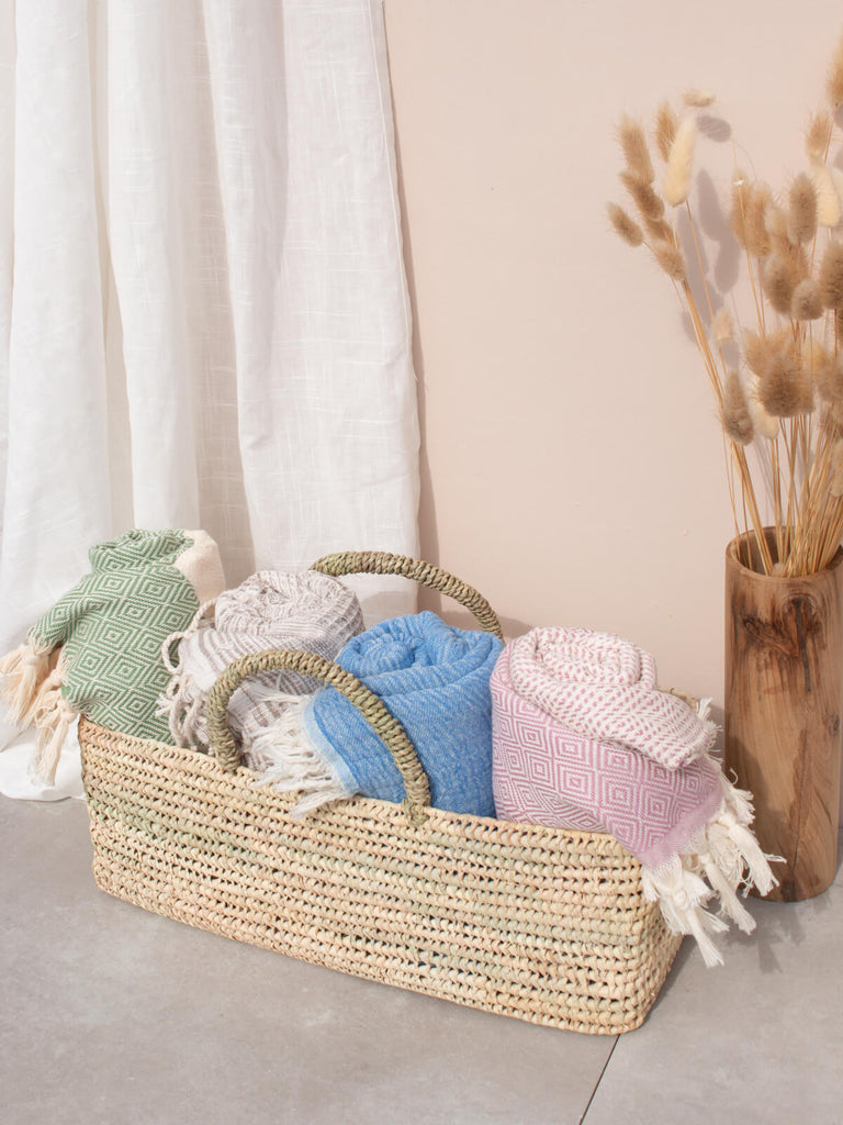 Long open weave storage basket filled with towels