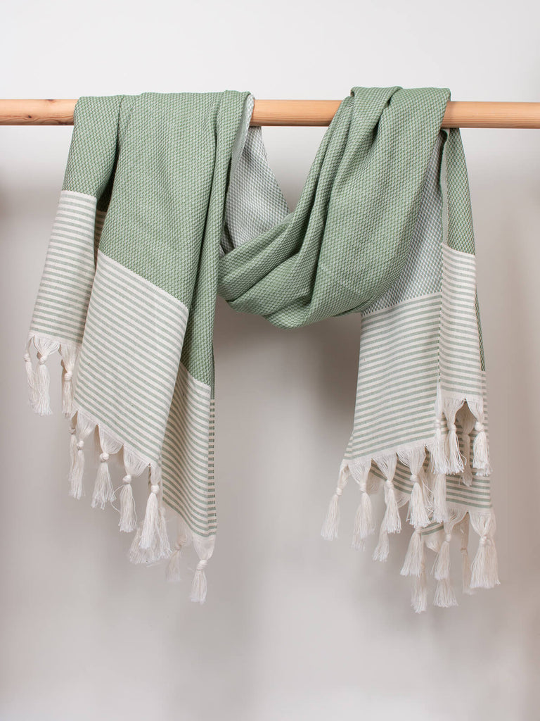Striped Amalfi Hammam Towel in olive stripe by Bohemia Design hanging on wooden rod