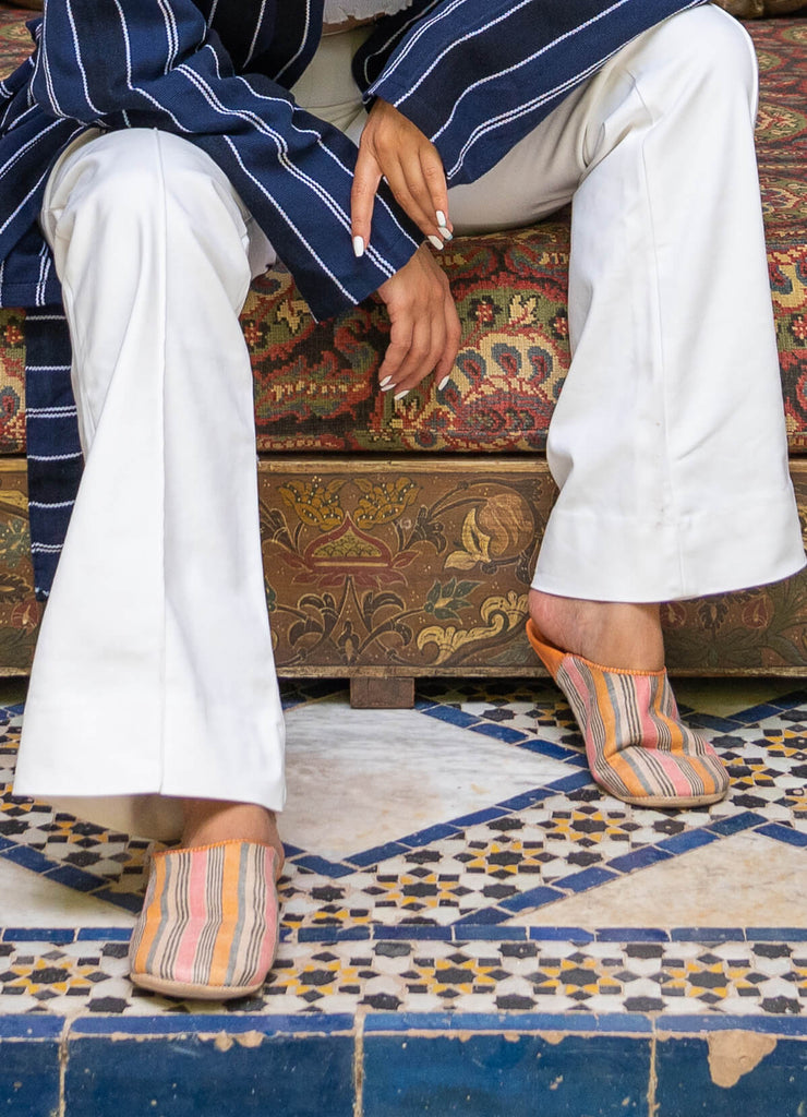 A woman wearing Linen and leather orange striped moroccan babouche slippers from the margot collection by Bohemia design