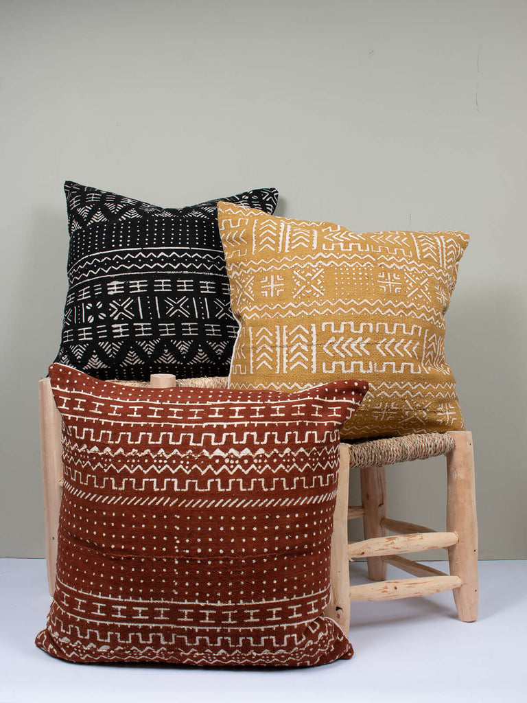 Three cushions in black, saffron, and tobacco with mudcloth patterns by Bohemia Design