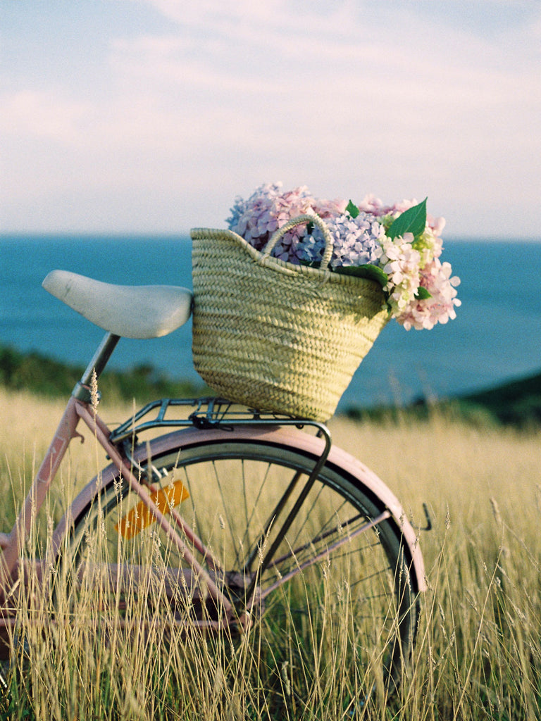 A Bohemia straw market basket on a pink bicycle