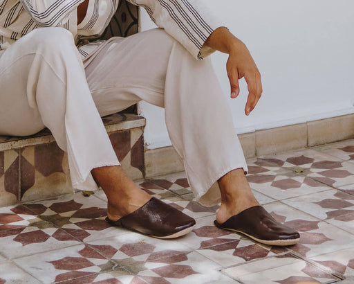 A seated man wearing a pair of Bohemia leather babouche slippers