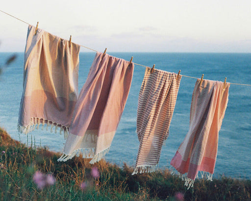 Pink striped hammam towels hanging on a washing line by the sea