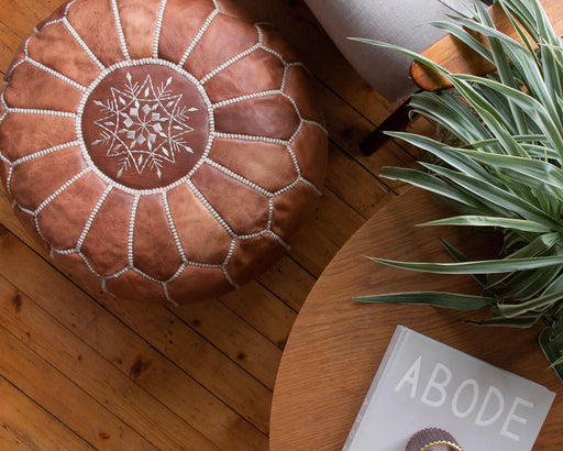 Moroccan leather pouffe on a wooden floor
