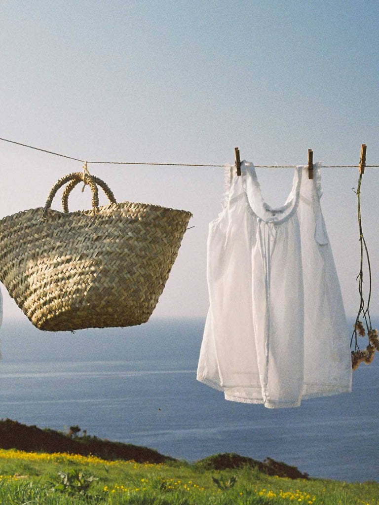 Small beldi storage basket being hung on a washing line alongside laundry and dried flowers