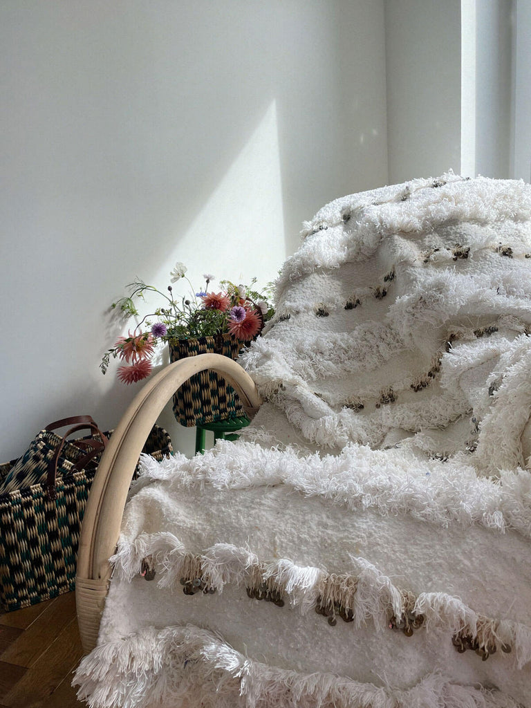 Vintage handira blanket with rows of fluffy wool fringing and sequins draped on a chair