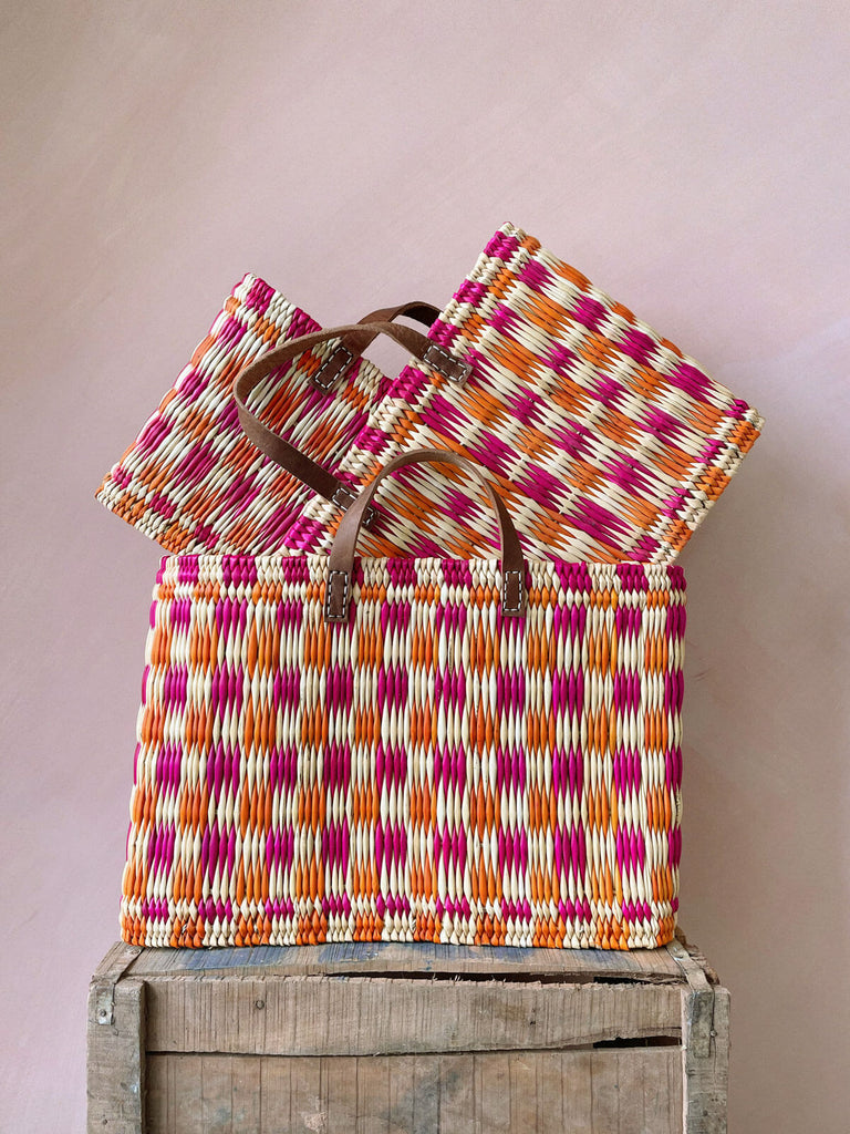 Set of three, rectangular, hand woven chequered reed basket bags with leather handles in pink and orange with short leather handles