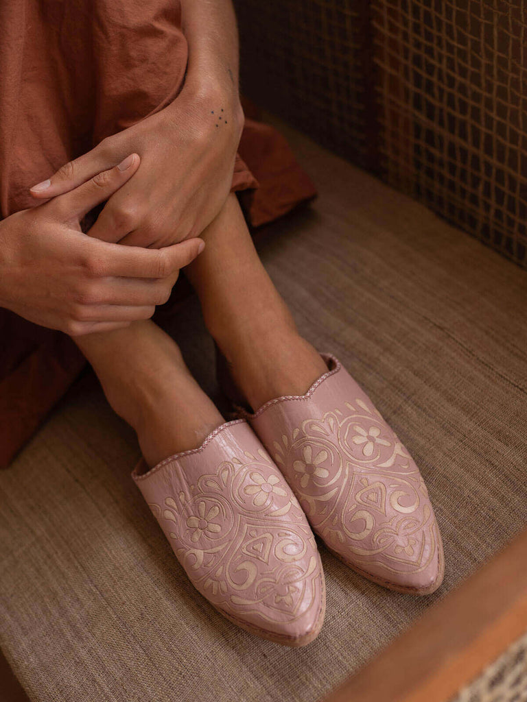 A pair of vintage pink decorative babouche slippers with heart pattern being worn by person in peach dress.