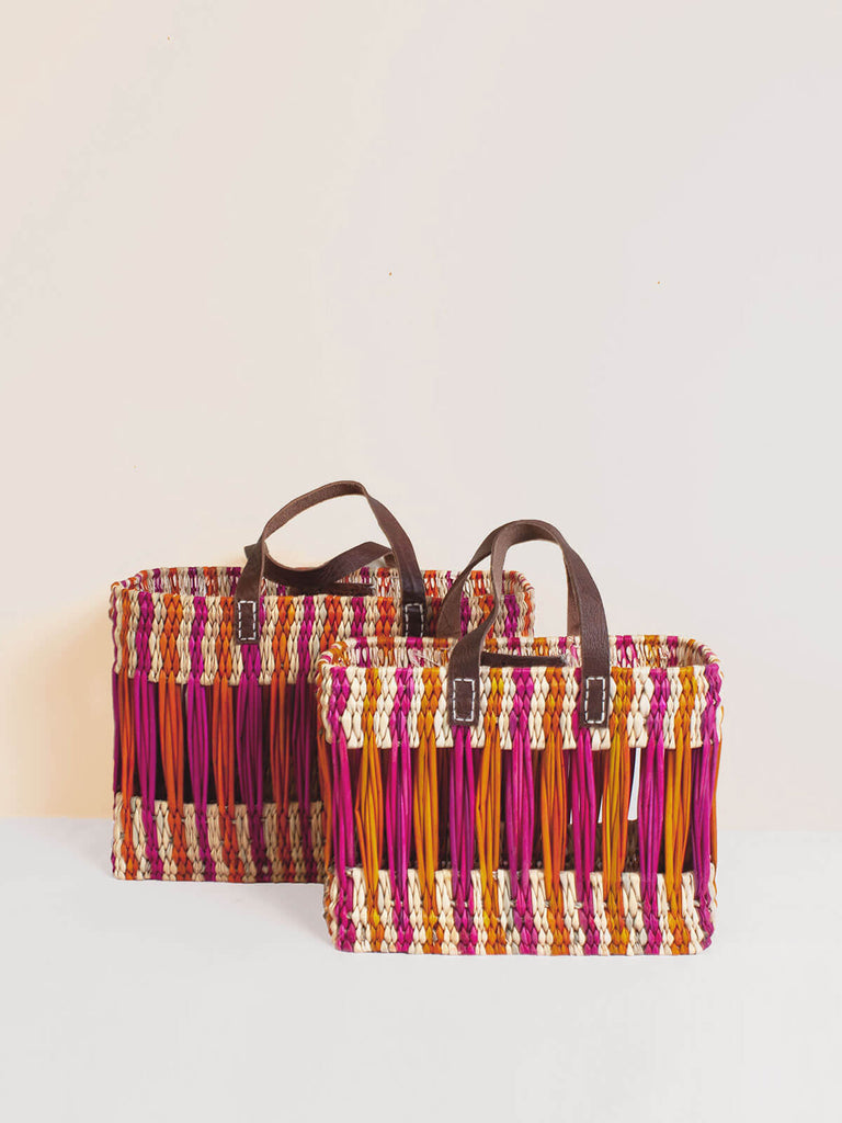 Two decorative woven reed rectangular basket bags with pink and orange stripes and short leather handles