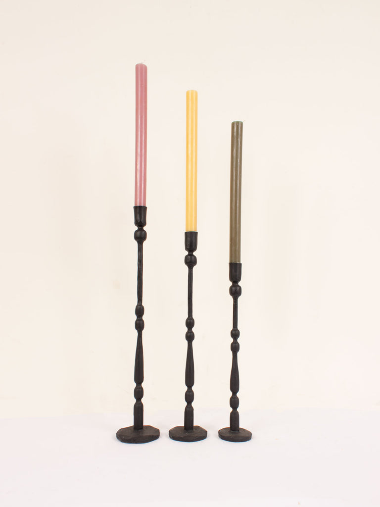 A row of 3 different sizes of black iron Eliot candleholders with colourful candles.