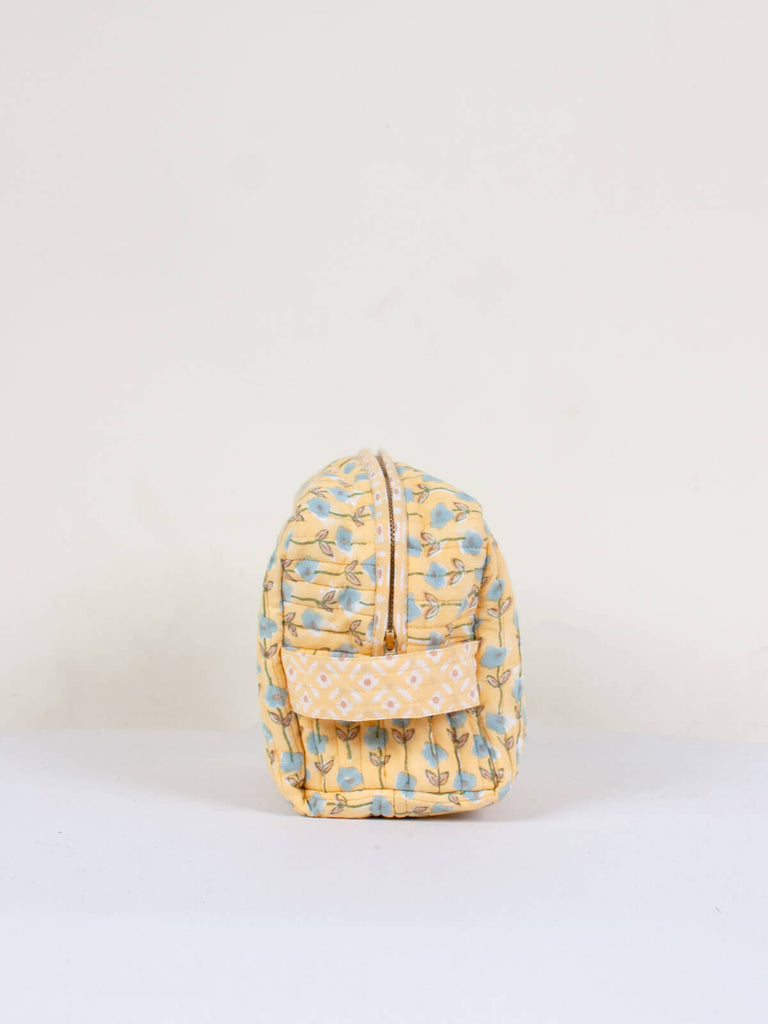 Side view showing carry handle of a quilted yellow and blue floral block print wash bag
