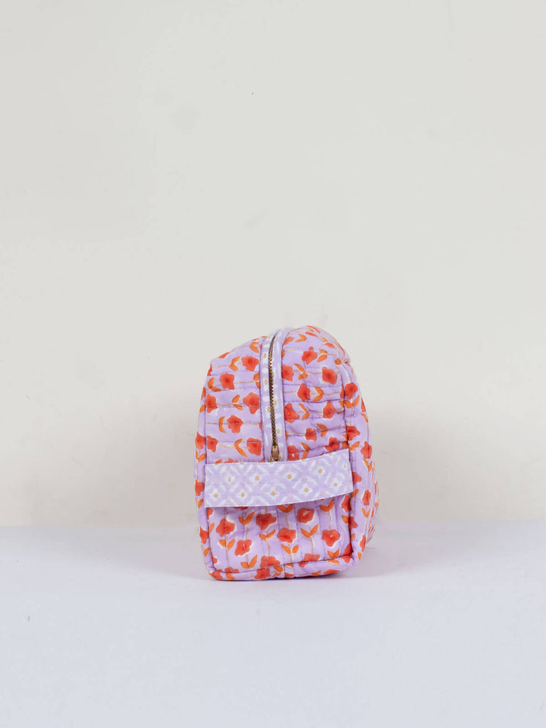Side view showing carry handle of a quilted lilac and orange floral block print wash bag
