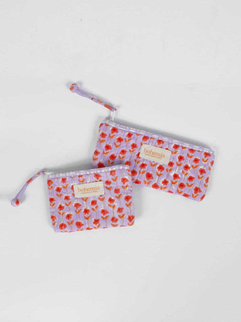 A small and long quilted cotton zip pouch with a lilac and orange ditsy floral print