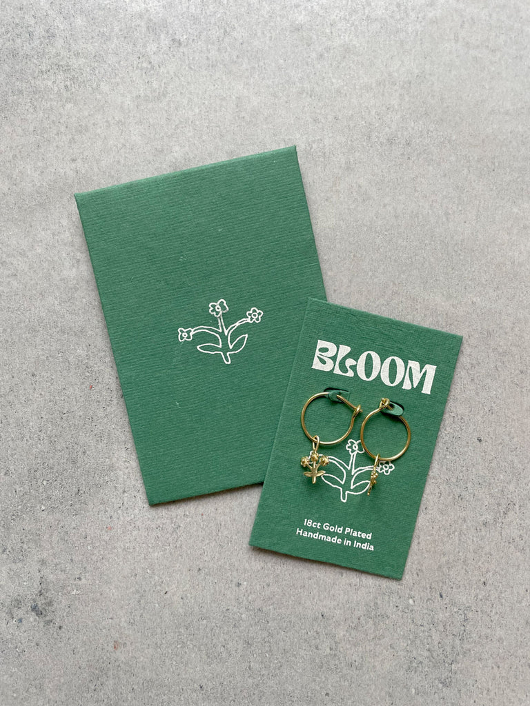 Gold posie hoop earrings on green cotton paper packaging made from textile offcuts