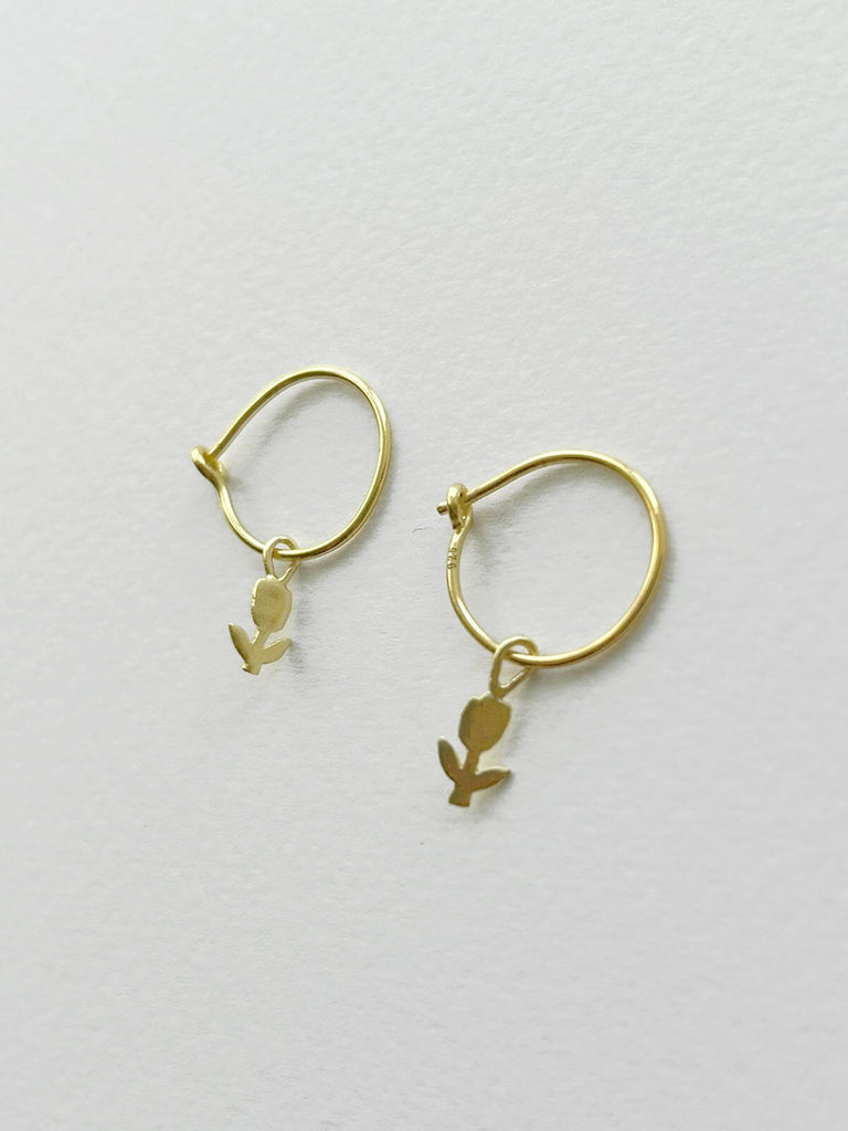 A pair of delicate gold hoop earrings with minimalist tulip design