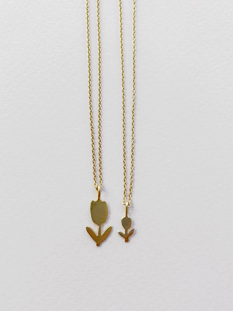 Small and tiny gold tulip necklaces on delicate fine gold chains side by side