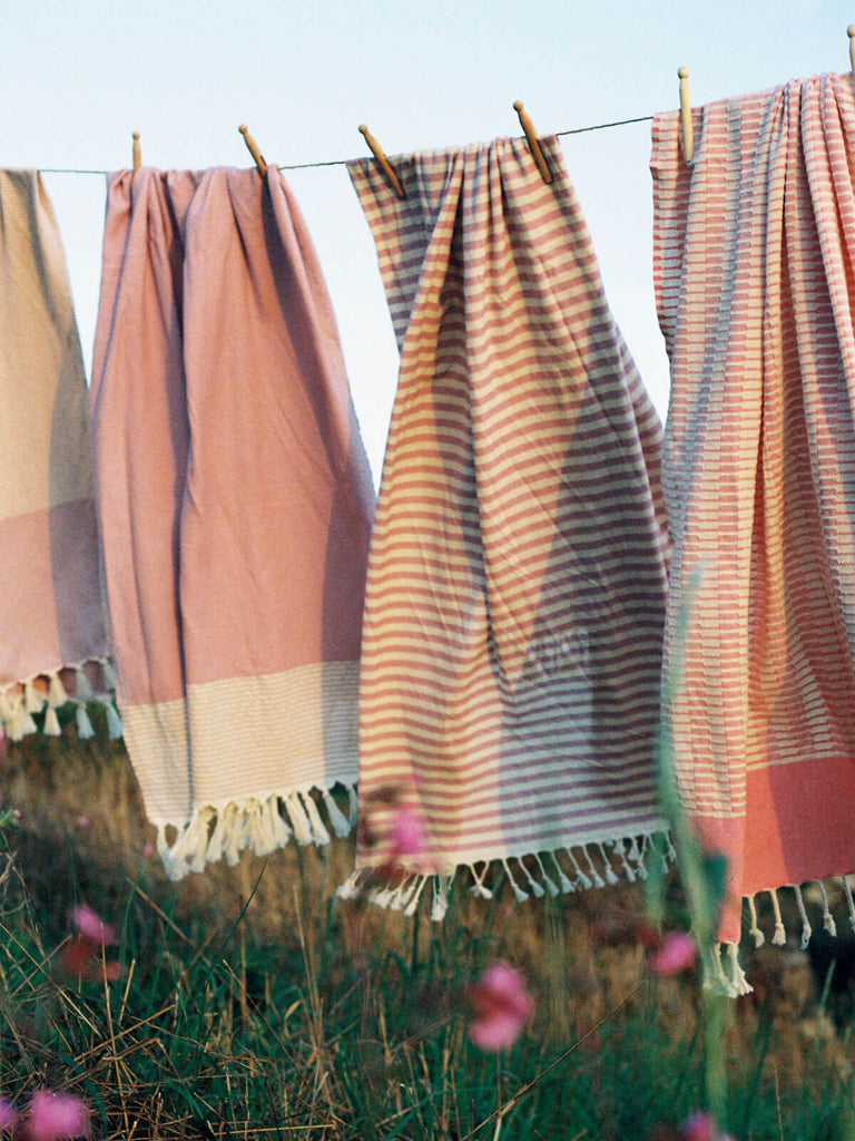 Pink striped hammam towels hanging on a line with wooden pegs