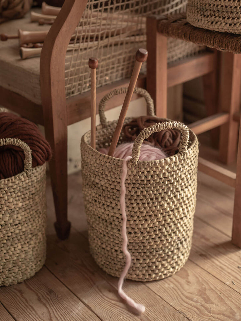 A nesting basket being used to hold wooden knitting needles and wool