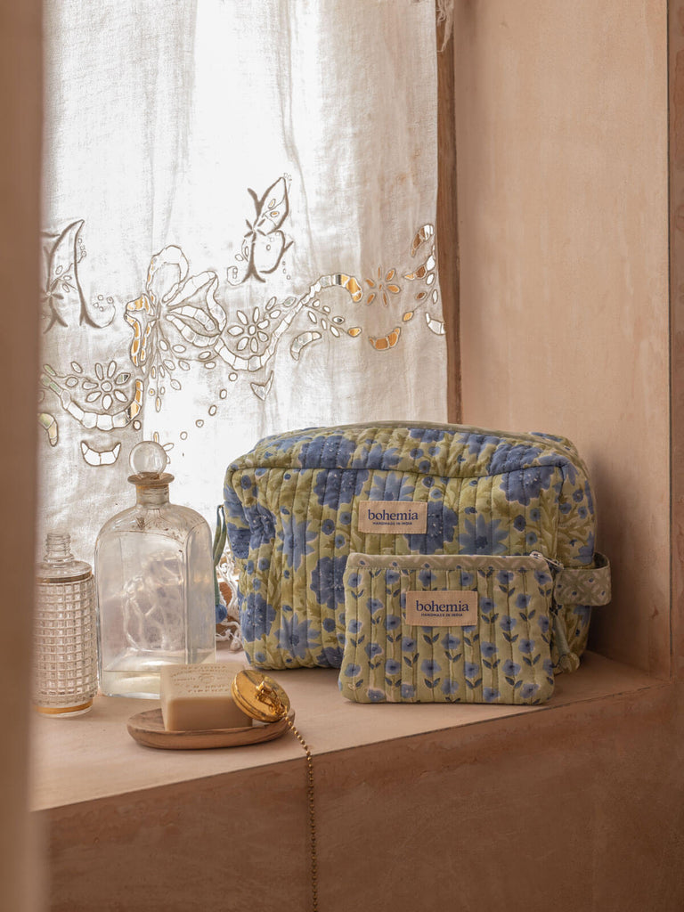 Floral print cotton quilted wash bag and zip pouch in sage green on a bathroom window sill
